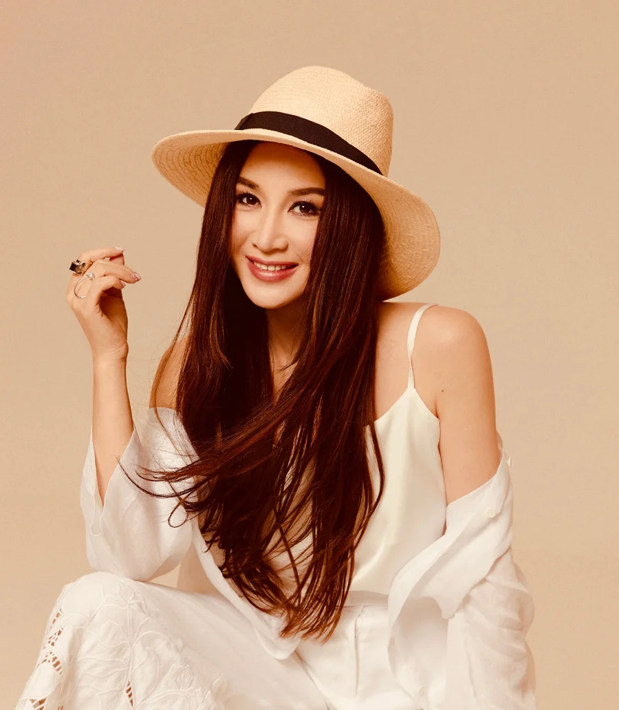 Ảnh chân dung Ôn Bích Hà đội mũ rộng vành, mặc trang phục trắng trong studio tông be ấm