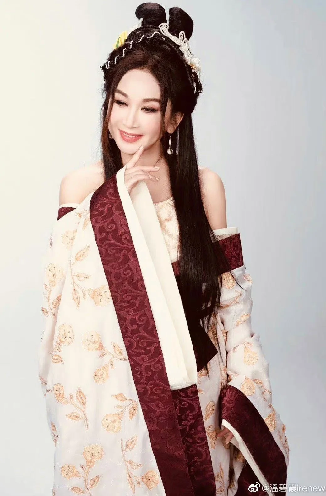 Ôn Bích Hà trong trang phục cổ trang Trung Hoa màu trắng và đỏ burgundy, tạo dáng thanh lịch với kiểu tóc búi cầu kỳ